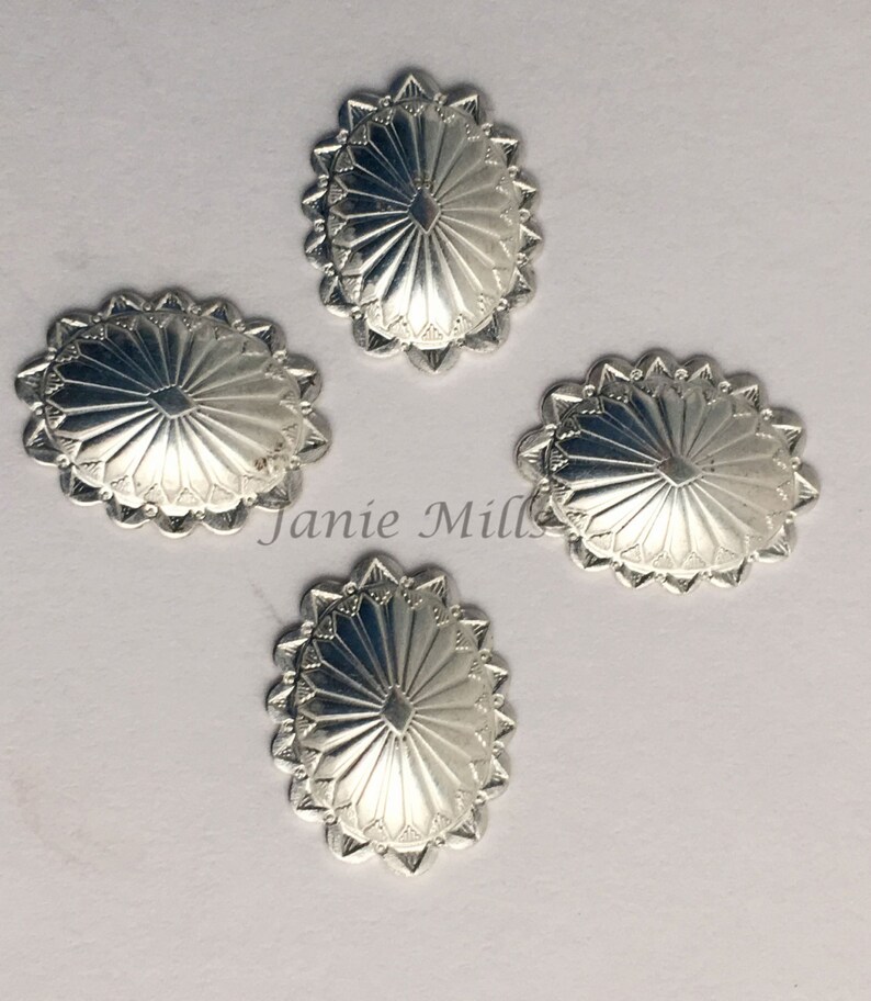 May include: Four silver-toned metal conchos with a sunburst design. Each concho has a scalloped edge.