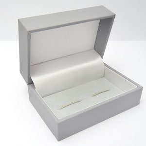 an open cufflink presentation box finished in grey with a white satin lining to the lid