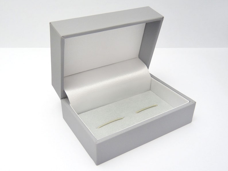 an open cufflink presentation box finished in grey with a white satin lining to the lid