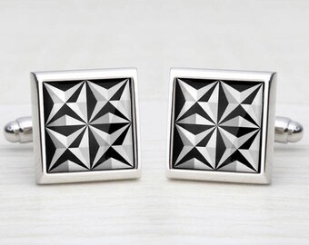 May include: A pair of silver cufflinks with a black and white geometric design.