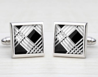 May include: A pair of silver cufflinks with a black and white geometric pattern.