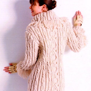 May include: A cream-coloured knitted sweater with a cable knit pattern and a fringe trim around the neck. The sweater has a high neck and long sleeves.