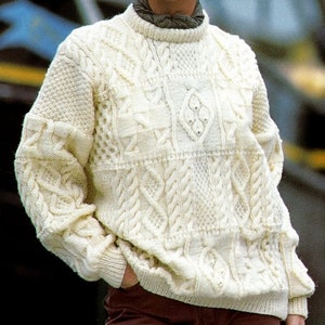 May include: A white knitted jumper with a cable knit pattern. The jumper has a crew neck and long sleeves.