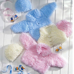 May include: Three knitted baby jackets in pink, blue and cream with matching hats. The jackets are made with a fluffy yarn and have a button closure.