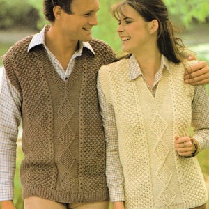 May include: A couple wearing matching knitted vests with a cable knit design. The man's vest is brown and the woman's vest is cream.