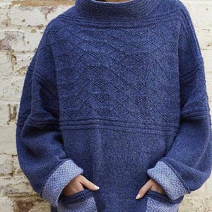 May include: A blue knitted sweater with a geometric pattern and two patch pockets. The sweater has a high neck and long sleeves.