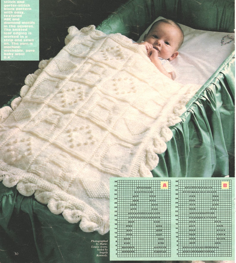 May include: A white knitted baby blanket with a diamond pattern and leaf edging. The blanket is machine washable and made of pure baby wool.