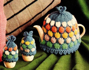May include: A set of three knitted tea cosy covers. The covers are blue with a pattern of colourful circles. The covers are for a teapot and two teacups.