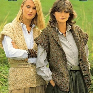 May include: Two women wearing knitted vests and collared shirts. One vest is beige, the other is brown with flecks of color. Both are belted at the waist. The woman on the left has blonde hair and the woman on the right has brown hair.
