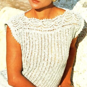 May include: A white crocheted top with a delicate lace pattern. The top has a scoop neckline and short sleeves.