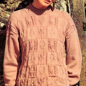 May include: A pink knitted sweater with a cable knit pattern. The sweater has a round neckline and long sleeves.