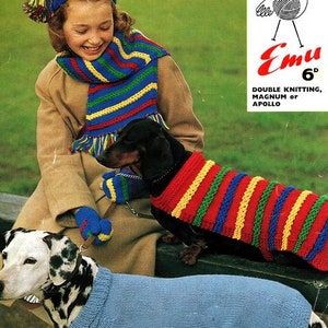 May include: A girl wearing a blue and yellow striped hat and scarf is holding a black and brown dachshund wearing a red, yellow and blue striped jumper. A dalmatian dog wearing a blue jumper is sitting in the foreground. The image includes the text "Emu 6d, Double Knitting, Magnum or Apollo".
