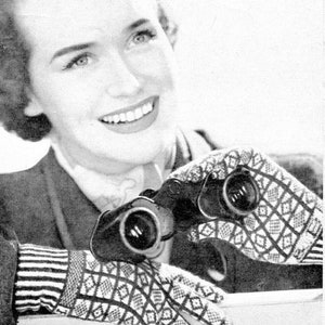 Può includere: Una donna indossa guanti di lana a maglia con motivi bianco e nero e tiene un binocolo.