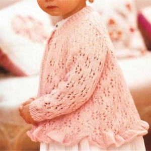 Peut inclure: Un cardigan rose clair en tricot, orné d'un motif floral et d'un ourlet à volants. Le pull à manches longues est fait d'un fil doux et léger, idéal pour être superposé. Le cardigan est conçu pour les enfants.