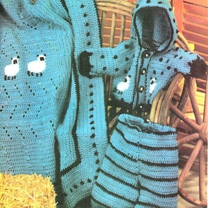 Könnte beinhalten: Ein gehäkeltes Layette-Set in Türkis, bestehend aus einer Kapuzenjacke, Shorts und einer Decke, mit schwarzen Verzierungen und weißen Lamm-Applikationen. Das Set wird auf einem Holzstuhl präsentiert. Der Text im Bild lautet: "Unser entzückendes Layette wurde aus Sportgewichtsgarn in Teal und Schwarz hergestellt, verziert mit weißen Lämmern."
