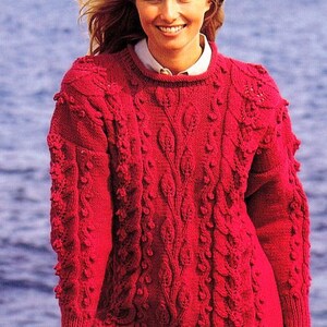 May include: A red knitted jumper with a cable knit pattern and a textured design. The jumper has a crew neck and long sleeves.