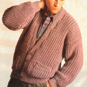 Op de afbeelding: Een roze gebreide cardigan met een V-hals, knoopsluiting en twee klepzakken. De cardigan is gemaakt met een textuur-steek.