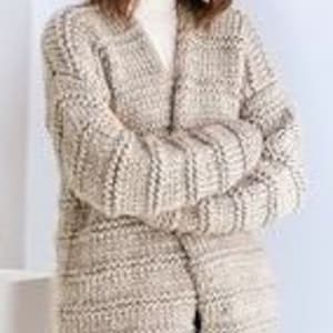 May include: A long, beige cardigan with a V-neck and a loose fit. The cardigan is made of a soft, textured yarn and has a relaxed, casual style.