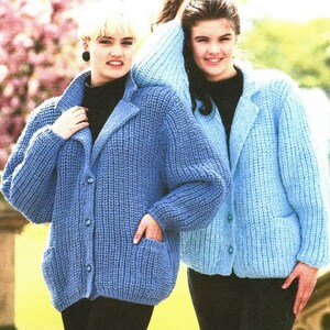 May include: Two women wearing blue knitted cardigans with button closures. The cardigan on the left is a darker shade of blue and has a pocket on each side. The cardigan on the right is a lighter shade of blue.
