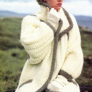 Peut inclure: Un cardigan en tricot blanc avec une bordure grise. Le cardigan a un col châle et est porté par une personne avec un bandeau bleu clair. Le cardigan est de taille 76-102 cm.
