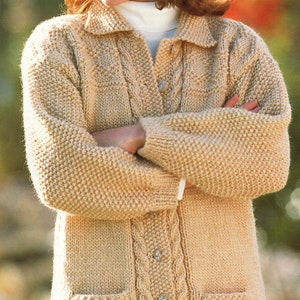 May include: A beige knitted cardigan with a cable knit design, button fastening, and two patch pockets.