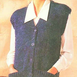 Op de afbeelding: Een blauwe gebreide vest met een knoopsluiting en twee zakken. De vest heeft een V-hals en wordt gedragen over een wit overhemd met kraag.