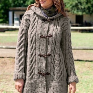 May include: A hooded cable knit cardigan with a brown toggle closure. The cardigan is a light brown color and has a relaxed fit.