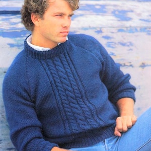 May include: A blue knitted sweater with a cable knit pattern. The sweater has a round neckline and long sleeves.