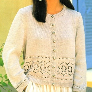 Puede incluir: Un cárdigan de punto color crema con cierre de botones y un borde de encaje alrededor del dobladillo. El cárdigan está hecho de un hilo suave y ligero y tiene un ajuste holgado.