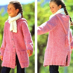 以下が含まれることがあります： フードとポケットが付いたピンクのニットカーディガン。カーディガンには白いニットのスカーフとフードにタッセルが付いています。