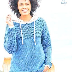 Puede incluir: Una sudadera con capucha azul tejida con una capucha beige claro y cordones blancos. El suéter tiene un patrón de tejido texturizado y se usa con jeans azules. Las palabras "Easy knit design" están en la esquina superior derecha.