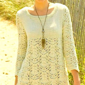May include: A light yellow knitted sweater with a delicate lace pattern and a long pendant necklace.