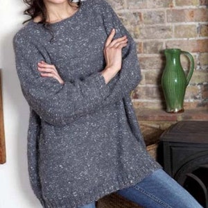 May include: A gray oversized sweater with a speckled pattern. The sweater has a round neckline and long sleeves.