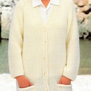Peut inclure: Un cardigan blanc en tricot avec un col en V, des manches longues et une fermeture à boutons. Le cardigan a deux poches sur le devant.