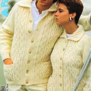 Könnte beinhalten: Zwei cremefarbene Strickjacken mit Zopfmuster, Knopfleiste und Taschen. Die Strickjacken sind aus weichem Garn gefertigt und haben ein klassisches Design.
