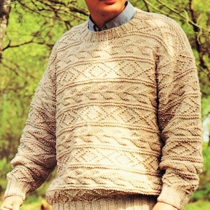 May include: A beige knitted jumper with a diamond pattern. The jumper has a crew neck and long sleeves.