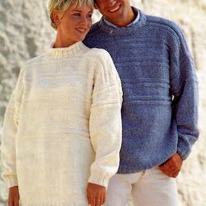 May include: Two people wearing jumpers, one white and one blue, with a textured pattern. They are standing in front of a white background.