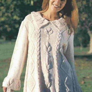 May include: A white knitted sweater with a cable knit design and a large collar. The sweater has a floral pattern on the front.