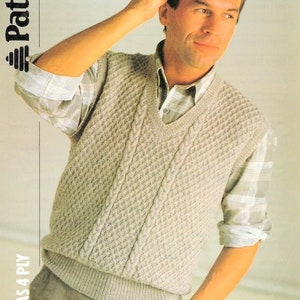 May include: A beige knitted vest with a cable knit pattern and a V-neck. The vest is worn over a plaid shirt.  The pattern number is 8235.  Knits as 4 ply.
