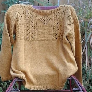 Peut inclure: Un pull en tricot jaune moutarde avec un délicat motif de dentelle autour du col et des épaules.
