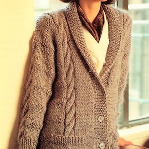 May include: A long-sleeved, knitted cardigan with a cable knit pattern and a shawl collar. The cardigan is a light brown color and has a button closure.