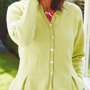 Puede incluir: Un cárdigan de punto verde claro con cierre de botones y un dobladillo con volantes.