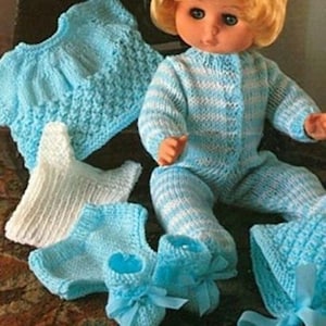 Puede incluir: Una muñeca vestida con un mono de punto a rayas azules y blancas, con botines de punto azules a juego, un gorro y un suéter de punto azul. También se incluyen calcetines de punto blancos. La muñeca tiene el pelo rubio y los ojos azules.