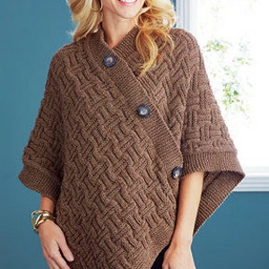 Könnte beinhalten: Ein braunes Strickponcho mit diagonalem Knopfverschluss. Das Poncho hat ein Zopfmuster und wird an einem Model gezeigt.