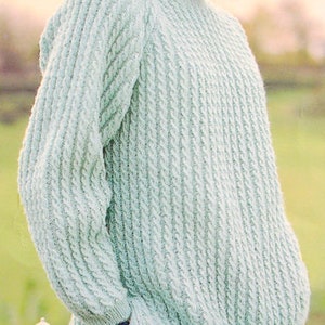 Könnte beinhalten: Ein hellgrüner Strickpullover mit Zopfmuster.