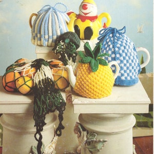 May include: A collection of crocheted tea cosy covers in various colours and patterns, including a pineapple, a clown, and a chequered design. The covers are displayed on white pedestals.