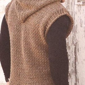 Peut inclure: Un gilet à capuche marron avec un motif en tricot texturé. Le gilet sans manches semble être fait d'une matière chaude, peut-être de la laine. La personne porte une chemise noire à manches longues en dessous. Le gilet a une capuche et un ourlet côtelé.