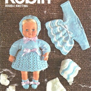 May include: A vintage knitting pattern cover with the word "Robin" and the number "2631". The image features a doll wearing a light blue knitted dress, bonnet, and booties. Additional knitted clothing items are also shown.