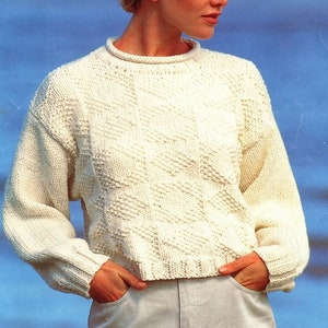 May include: A white knitted sweater with a diagonal pattern. The sweater has a round neckline and long sleeves.