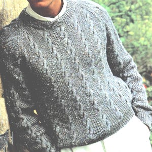 May include: A gray cable-knit sweater with a crew neck. The sweater has a textured pattern and long sleeves. The garment is made of a soft, warm material, perfect for cooler weather.
